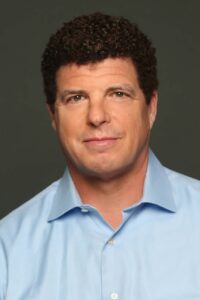 Portrait of a man in a light blue collared shirt against a plain background.